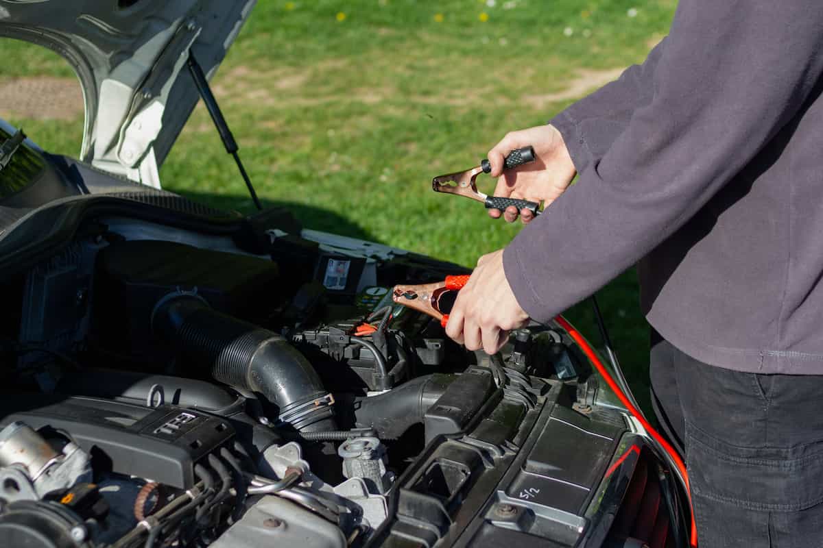 Mobile mechanic working under the hood of a car in a residential driveway